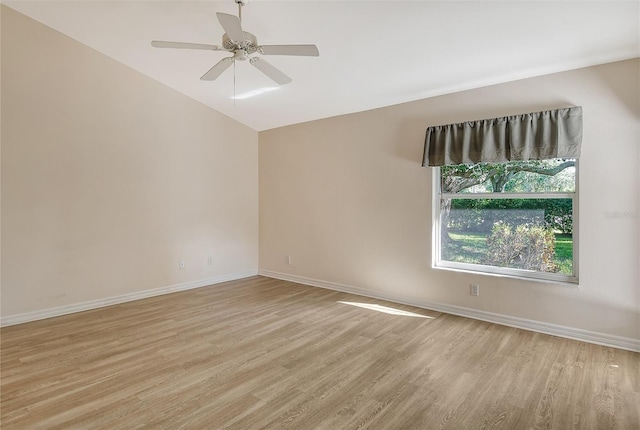 empty room featuring lofted ceiling, light wood-style flooring, baseboards, and a ceiling fan