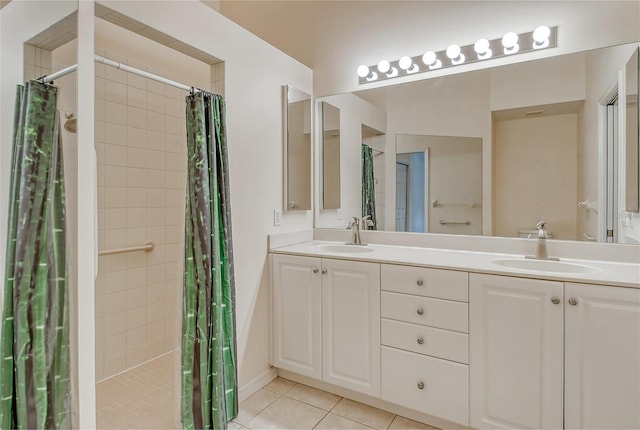 bathroom with tile patterned flooring, tiled shower, a sink, and double vanity