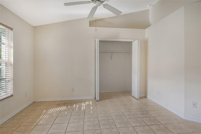 unfurnished bedroom featuring vaulted ceiling, a closet, light tile patterned flooring, and baseboards