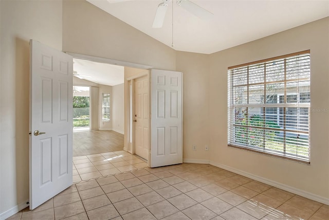 empty room with lofted ceiling, ceiling fan, baseboards, and light tile patterned floors