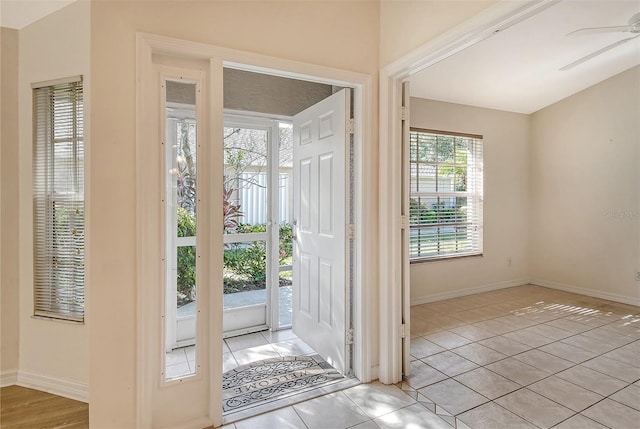 doorway to outside featuring a ceiling fan, baseboards, and light tile patterned floors