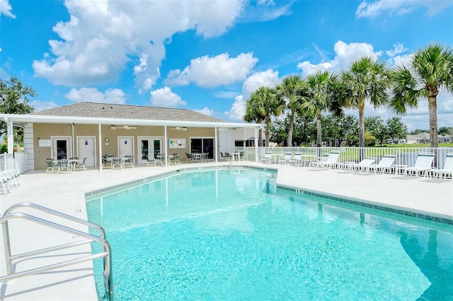 pool with french doors, a patio area, and fence