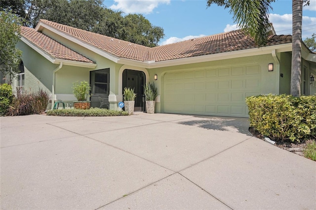 view of front facade featuring an attached garage, a tile roof, and stucco siding