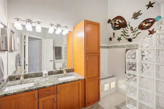 full bathroom with double vanity, a sink, toilet, and walk in shower