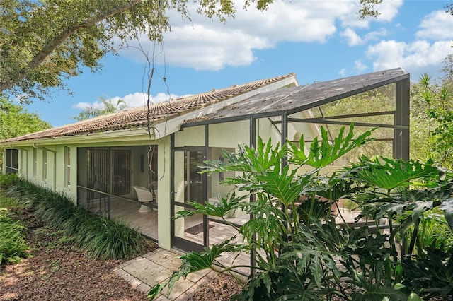 back of house featuring glass enclosure and a tiled roof