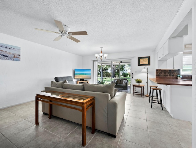 living room with a textured ceiling, a healthy amount of sunlight, ceiling fan with notable chandelier, and light tile patterned flooring