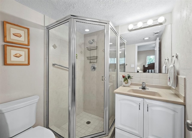 bathroom featuring a textured ceiling, vanity, toilet, and a shower with shower door