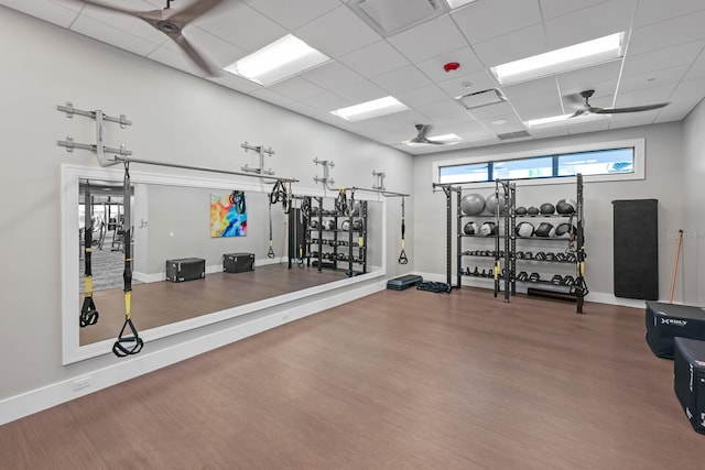 workout area featuring ceiling fan, a drop ceiling, and wood-type flooring