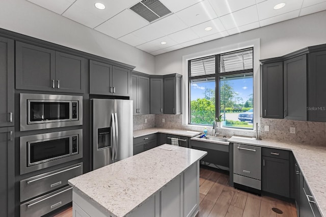 kitchen featuring dark hardwood / wood-style floors, light stone countertops, stainless steel appliances, and a center island