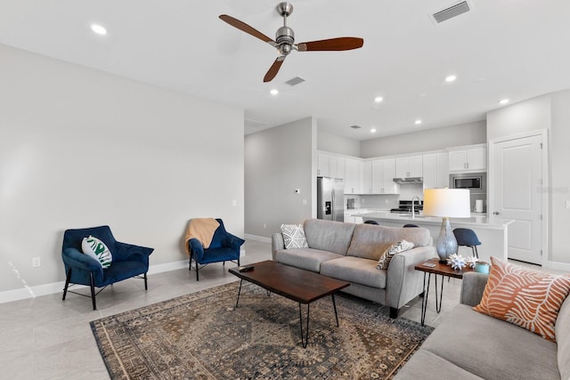 living room featuring ceiling fan, light tile patterned floors, and sink