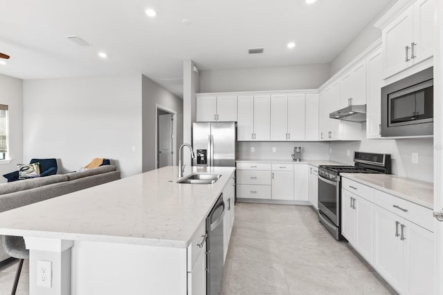 kitchen with white cabinetry, a center island with sink, stainless steel appliances, light stone countertops, and sink