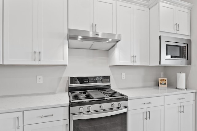 kitchen featuring stainless steel appliances, white cabinetry, and light stone counters