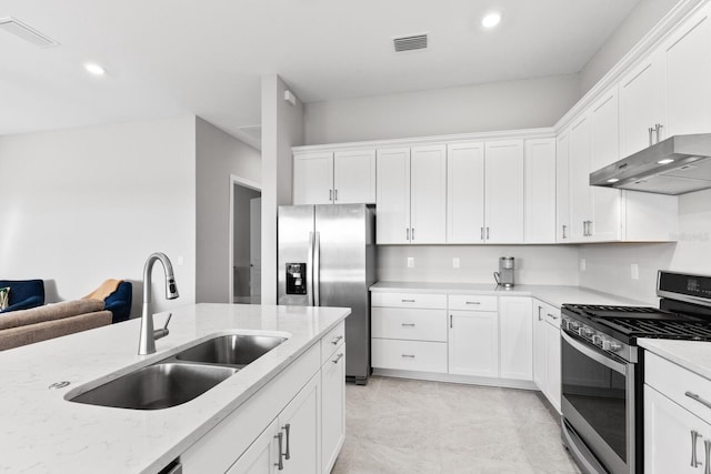 kitchen featuring appliances with stainless steel finishes, sink, light stone counters, and white cabinets