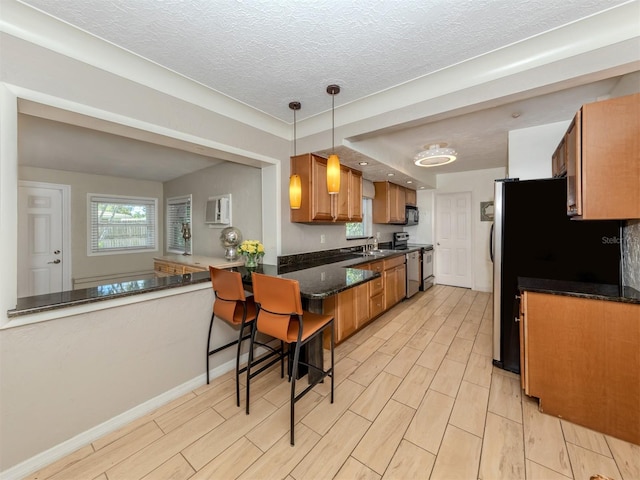 kitchen with electric range, sink, hanging light fixtures, kitchen peninsula, and a breakfast bar