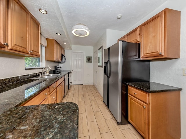 kitchen with dark stone counters, sink, and stainless steel appliances