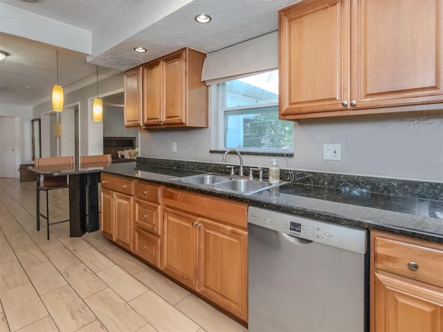 kitchen featuring dishwasher, dark stone counters, decorative light fixtures, and sink