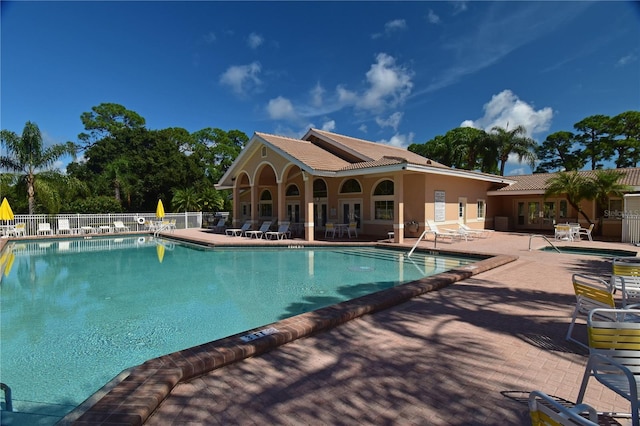 community pool with fence and a patio