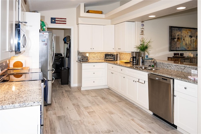 kitchen featuring appliances with stainless steel finishes, light stone counters, tasteful backsplash, white cabinets, and vaulted ceiling