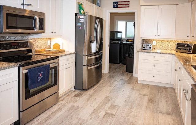 kitchen with white cabinets, light wood-style floors, light stone counters, and stainless steel appliances