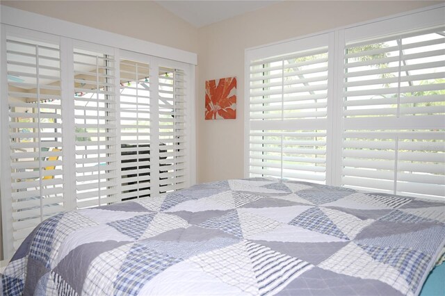 bedroom with vaulted ceiling and multiple windows