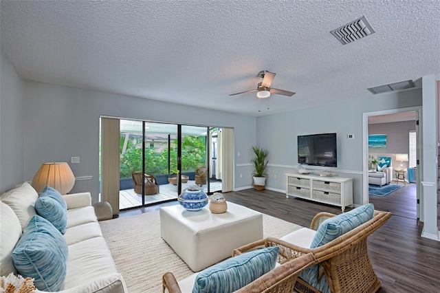 living room featuring ceiling fan, a textured ceiling, and dark wood-type flooring