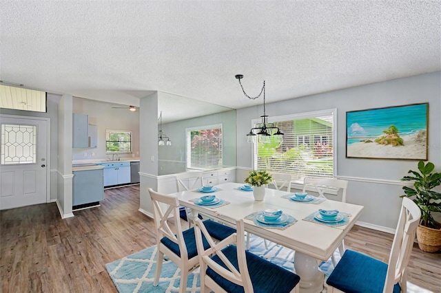 dining space with hardwood / wood-style flooring, a notable chandelier, a textured ceiling, and sink