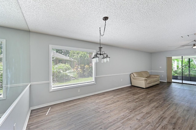 empty room with a textured ceiling, hardwood / wood-style floors, and a healthy amount of sunlight