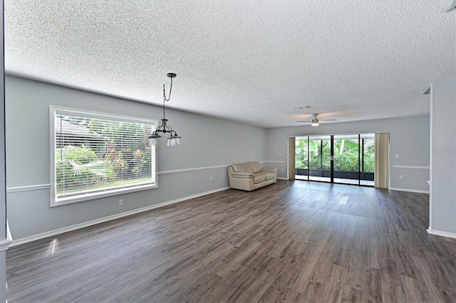 unfurnished living room with dark hardwood / wood-style flooring, a textured ceiling, and a healthy amount of sunlight