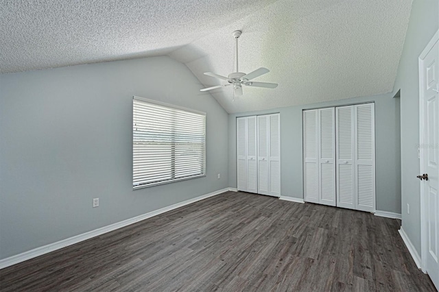 unfurnished bedroom featuring multiple closets, a textured ceiling, lofted ceiling, dark hardwood / wood-style flooring, and ceiling fan