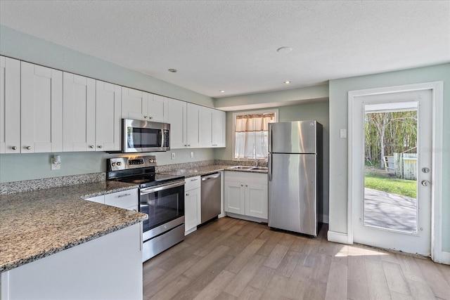 kitchen featuring appliances with stainless steel finishes, light wood-type flooring, and white cabinets