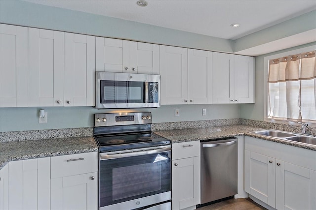 kitchen featuring sink, stainless steel appliances, dark stone counters, and white cabinetry