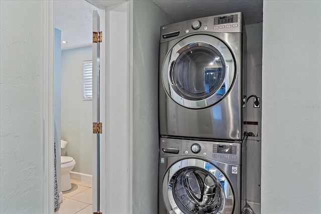 laundry area featuring light tile patterned flooring and stacked washer / dryer