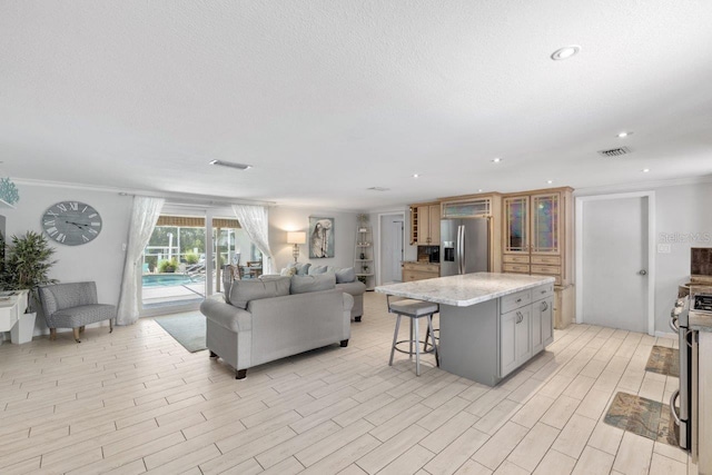 interior space featuring a kitchen bar, stainless steel appliances, crown molding, a center island, and gray cabinets