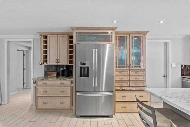 kitchen with light brown cabinets, stone counters, decorative backsplash, stainless steel fridge, and ornamental molding