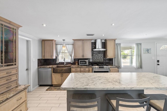 kitchen featuring wall chimney exhaust hood, a breakfast bar, stainless steel appliances, sink, and a center island