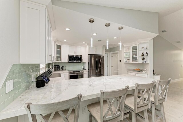 kitchen featuring kitchen peninsula, appliances with stainless steel finishes, a breakfast bar, and white cabinets