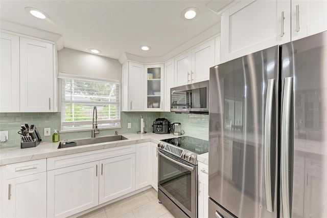 kitchen featuring sink, light tile patterned floors, light stone counters, white cabinetry, and stainless steel appliances