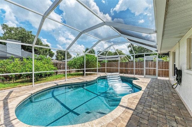 view of pool with glass enclosure and a patio area