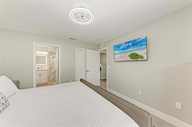 bedroom featuring connected bathroom and washer / dryer