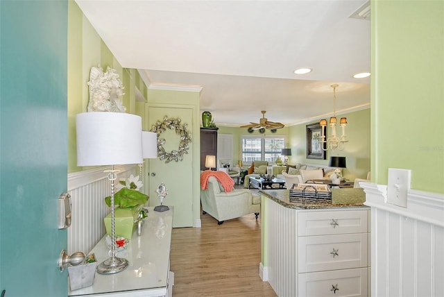 kitchen with light wood-style floors, ornamental molding, wainscoting, and white cabinets