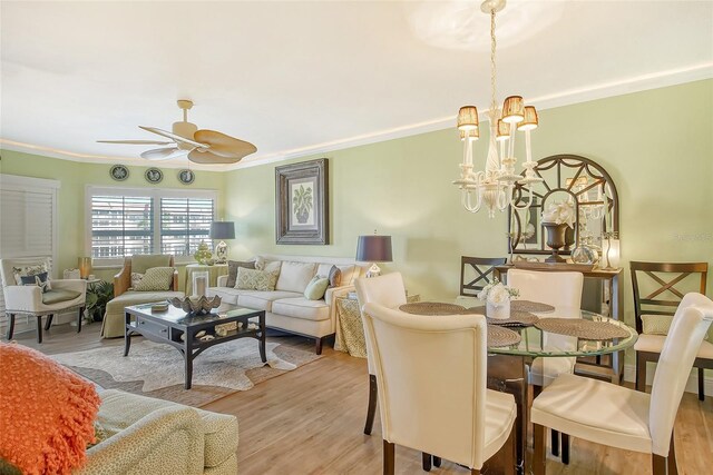 dining space with ceiling fan with notable chandelier, crown molding, and light hardwood / wood-style floors