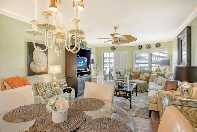 living room with ceiling fan with notable chandelier, crown molding, and wood-type flooring