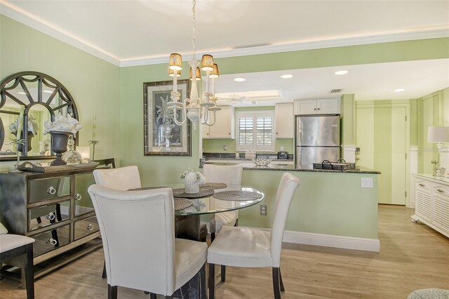 dining room with crown molding, light hardwood / wood-style flooring, and a chandelier