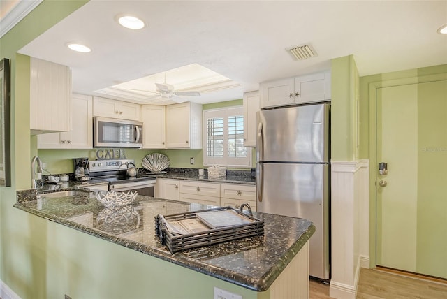 kitchen featuring dark stone countertops, stainless steel appliances, sink, kitchen peninsula, and ceiling fan