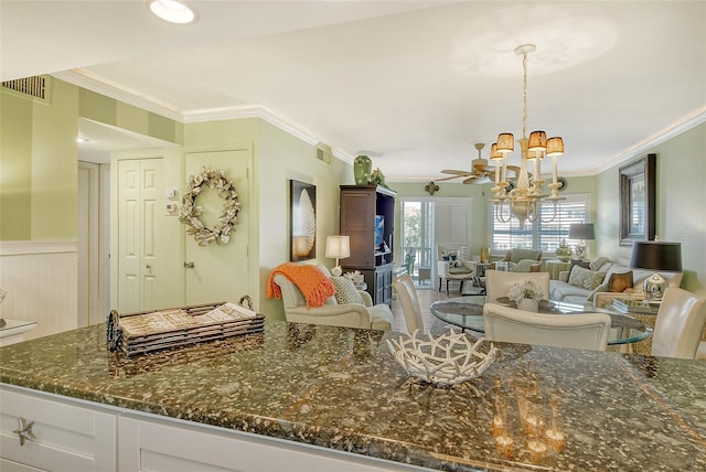 kitchen featuring crown molding, dark stone counters, ceiling fan with notable chandelier, and white cabinets