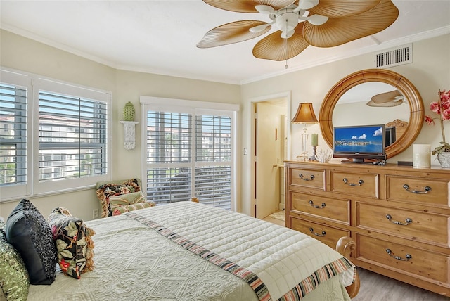 bedroom featuring light hardwood / wood-style flooring, ceiling fan, ornamental molding, and multiple windows