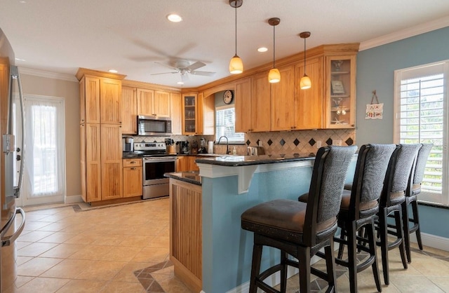 kitchen with kitchen peninsula, a breakfast bar, stainless steel appliances, ceiling fan, and light tile patterned floors