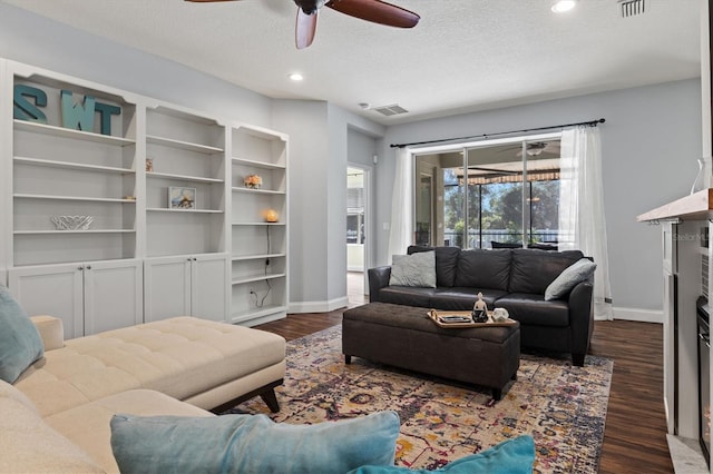 living room featuring ceiling fan, dark wood-type flooring, and a textured ceiling