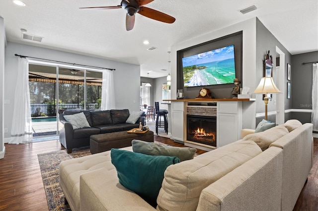 living room with dark wood-type flooring, visible vents, and a lit fireplace