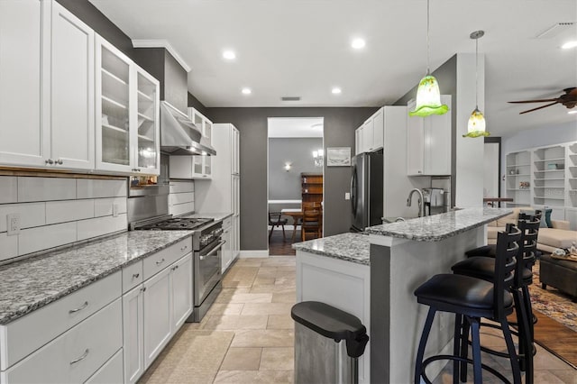 kitchen with stainless steel stove, white cabinets, a breakfast bar area, and light stone countertops